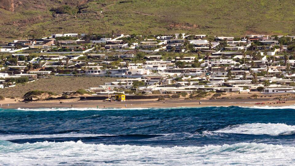 A coastal town with houses along the beach and waves crashing onto the shore.
