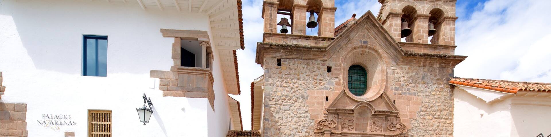 A historic building with a white facade and a stone bell tower.