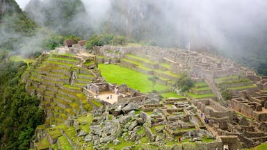 The ruins of Machu Picchu, featuring terraced stone structures, a central plaza, and surrounding lush greenery.