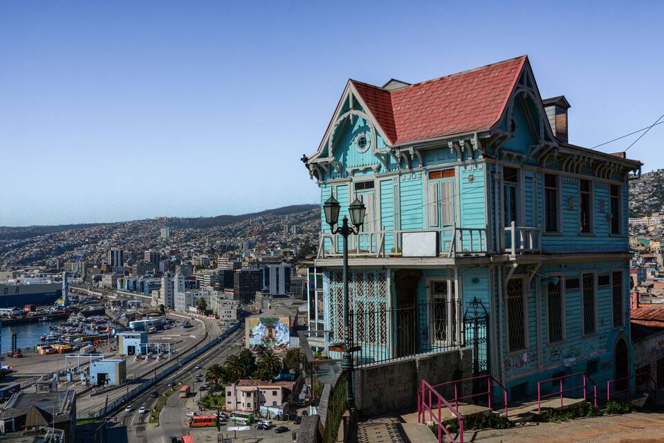 A turquoise building with a red roof overlooking a cityscape.