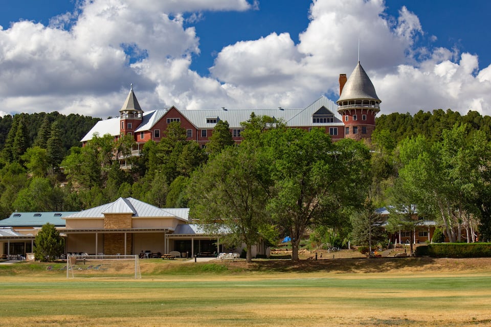 A large estate with a prominent tower and a tennis court in the foreground.