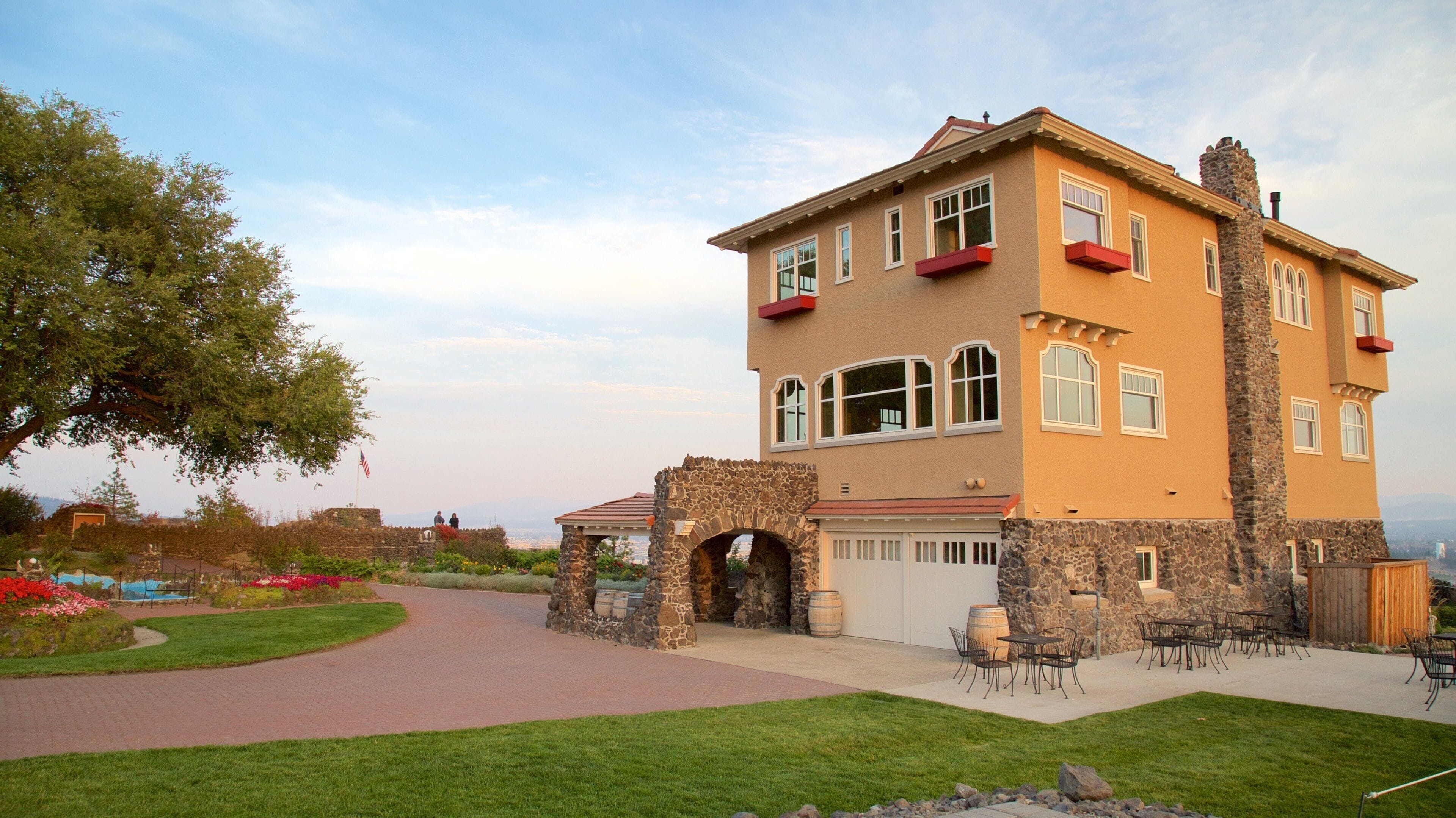 A large, two-story house with a stone facade, a red roof, and a stone archway at the entrance.