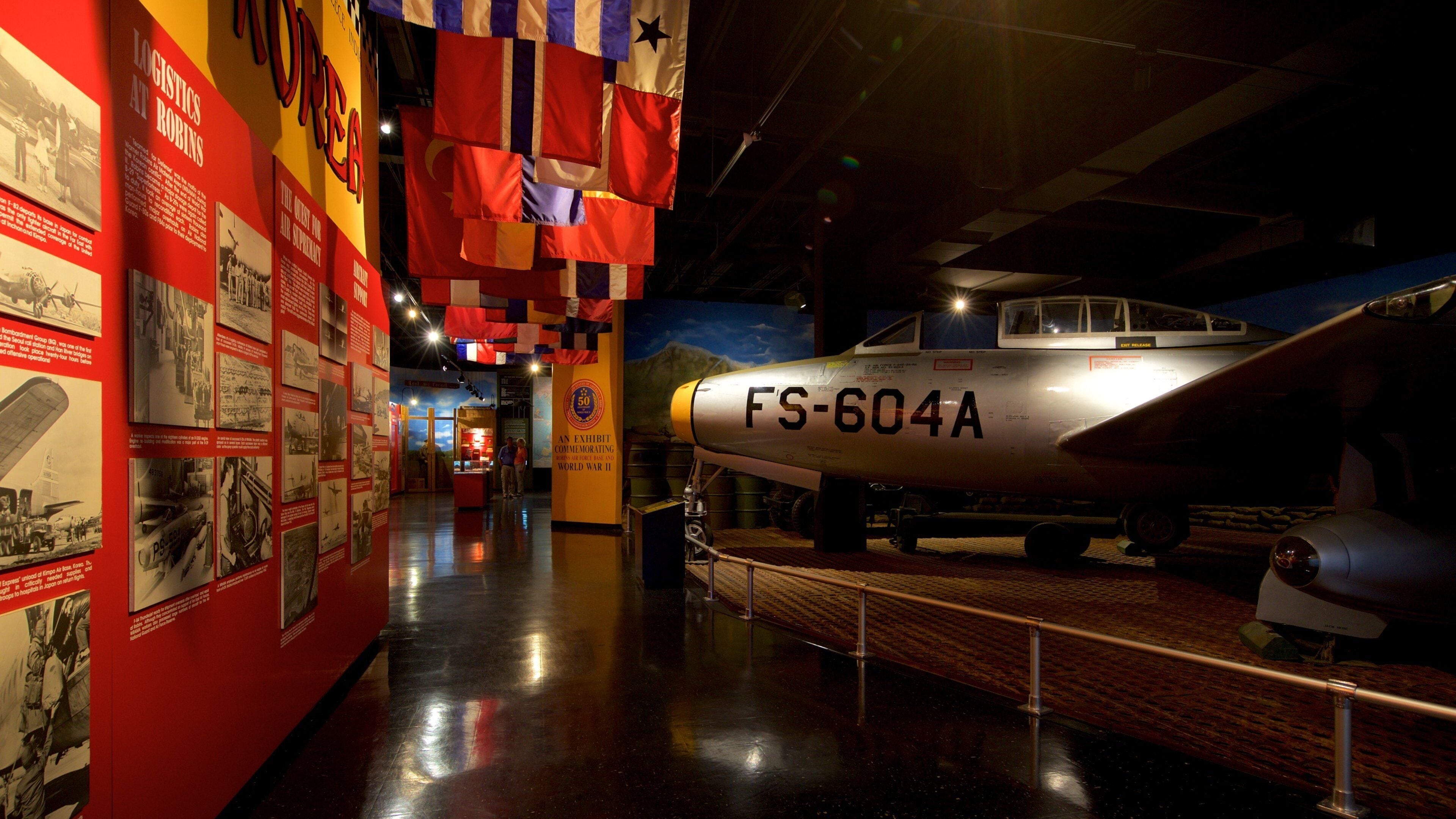 A museum exhibit with a WWII bomber aircraft, informational displays, and hanging flags.