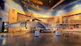 A fighter jet in a museum with a sky mural and other aircraft models.