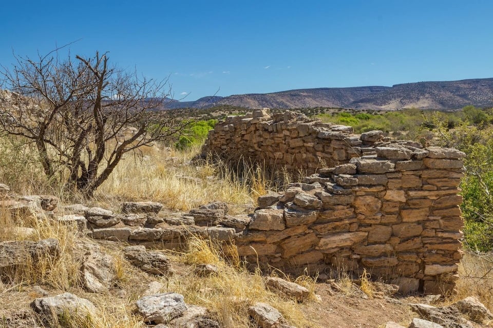 A stone ruin in a dry, hilly landscape with sparse vegetation.