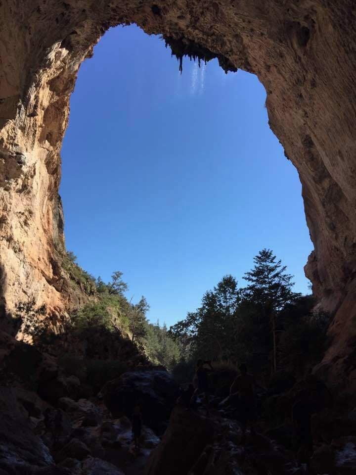 A cave entrance with a clear blue sky visible through the arch.