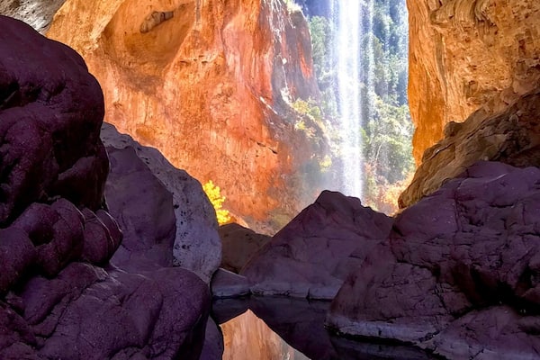 Eine Höhle mit einem natürlichen Torbogen und einem Wasserfall.