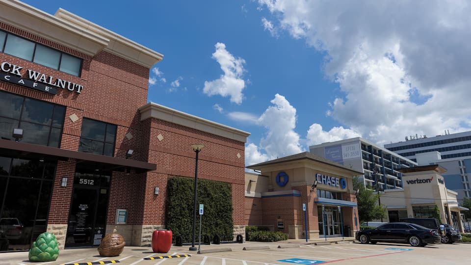 Um prédio comercial com a placa 'Black Walnut Cafe', um banco 'Chase' e uma loja da Verizon.