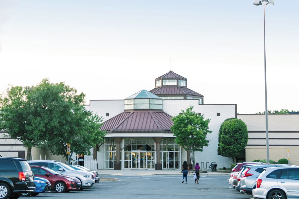 A parking lot with several cars and a building with a distinctive roof and entrance.