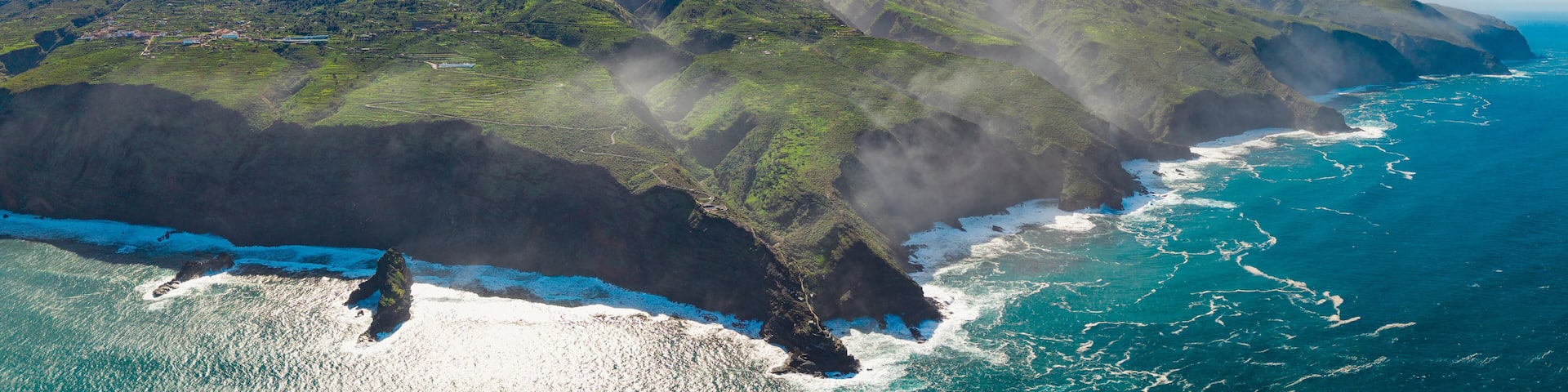 Aerial view of rugged coastline with waves crashing against cliffs and panoramic landscape, Garafia town, La Palma Island, Canary Islands, Spain.