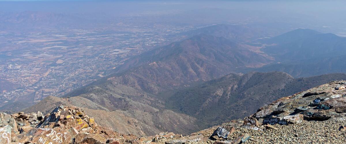A mountainous landscape with rocky terrain and distant city views.