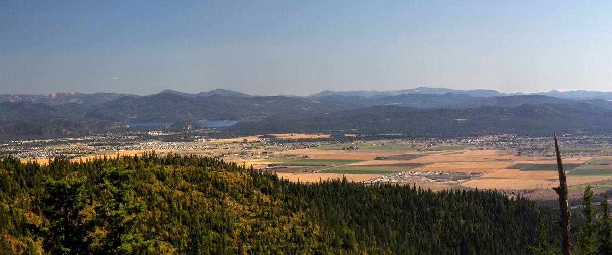 A mountainous landscape with a town in the valley, surrounded by forests and fields.