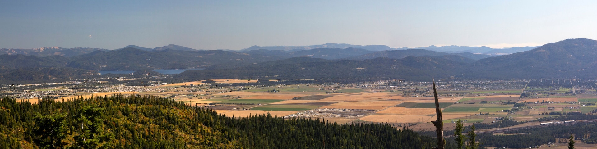 A mountainous landscape with a town in the valley, surrounded by forests and fields.