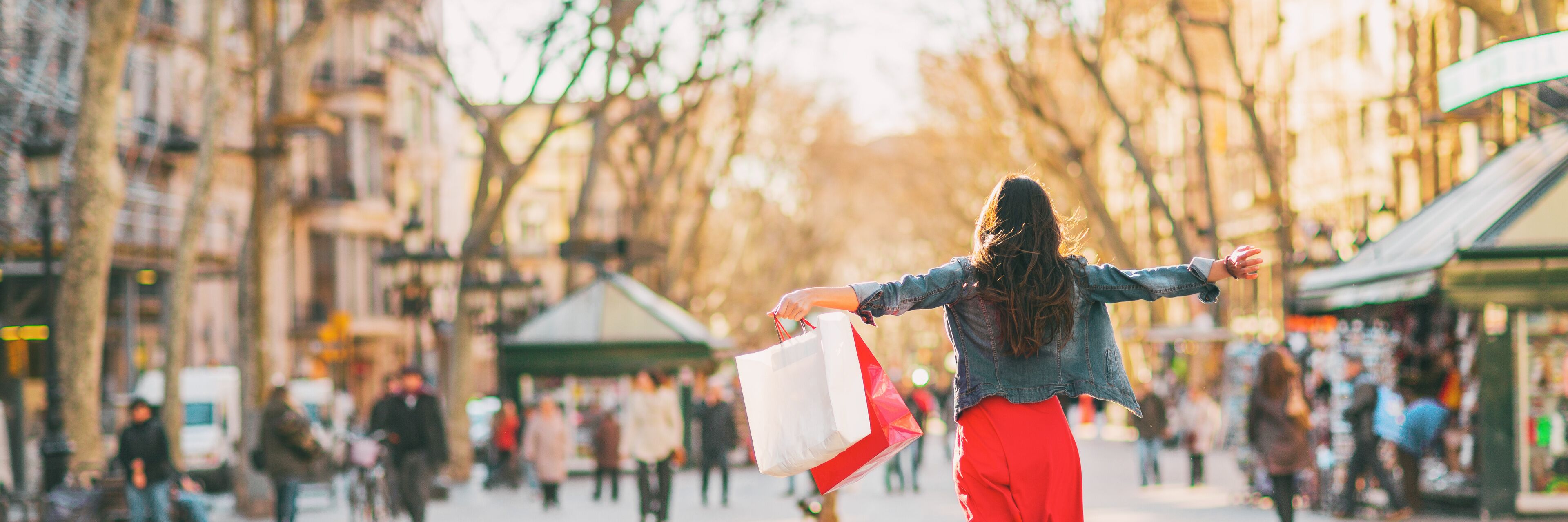 Shopping fun happy woman with bags spending buying new clothes in stores of Barcelona, Spain. Panoramic banner of happy girl with open arms in freedom.