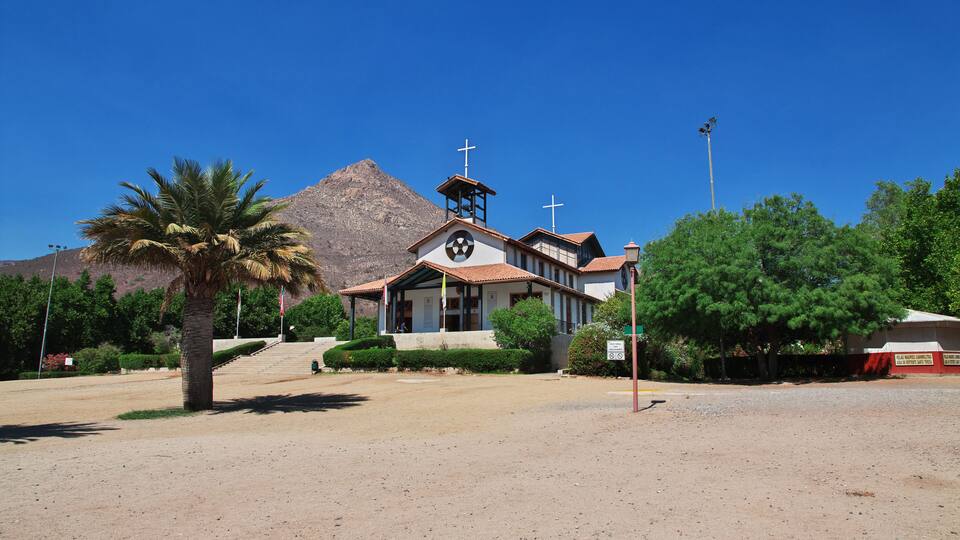 A church with a bell tower and a mountain in the background.