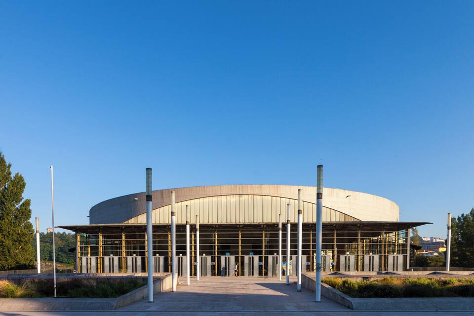A modern architectural building with a curved facade and a series of vertical columns.