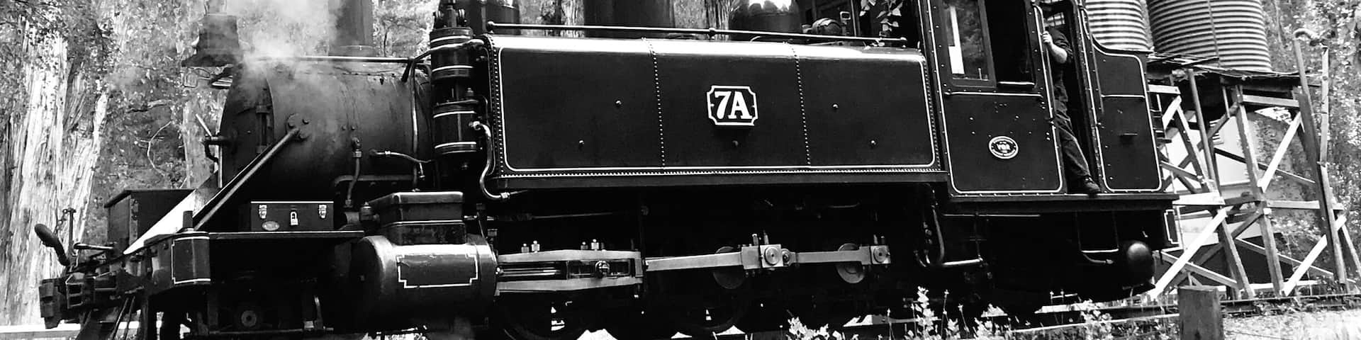 A steam locomotive with the number 7A on a railway track surrounded by trees.