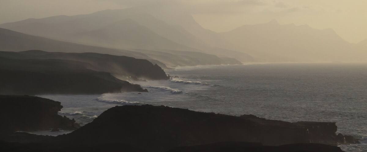 A coastal landscape with rugged cliffs and a misty sea.