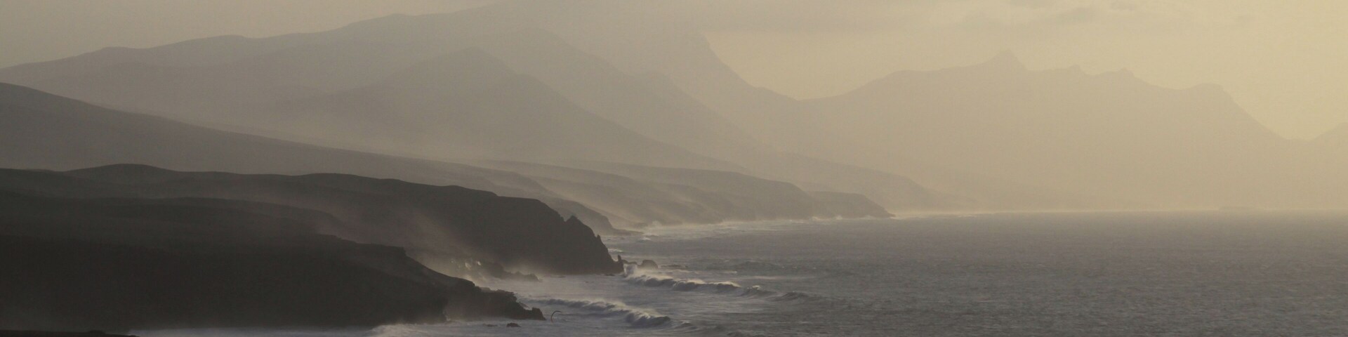 A coastal landscape with rugged cliffs and a misty sea.