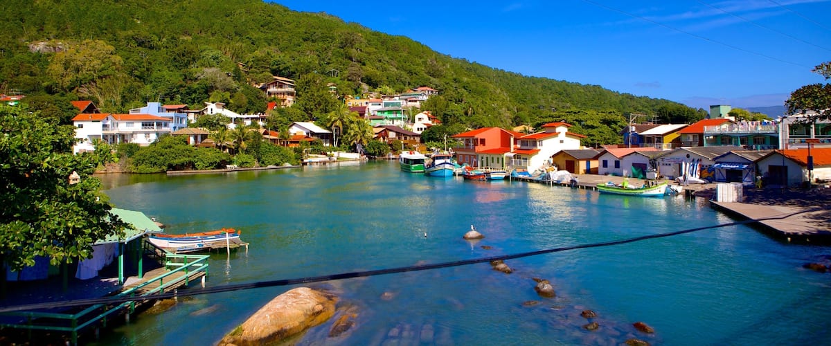 A coastal town with colorful houses, a clear blue sky, and a calm harbor with boats.