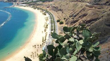 A coastal landscape with a beach, a road, and a mountain.