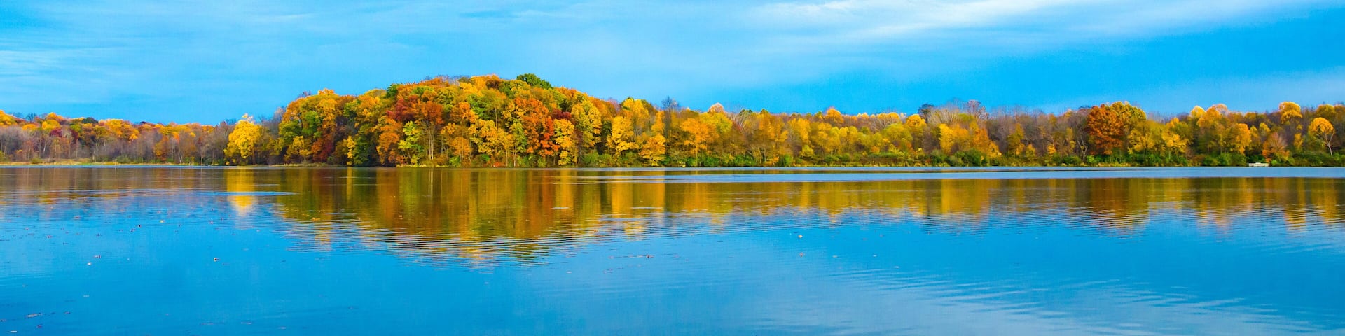 An island of fall colors sandwiched between blue sky and water at Potato Creek State Park in North Liberty, Indiana