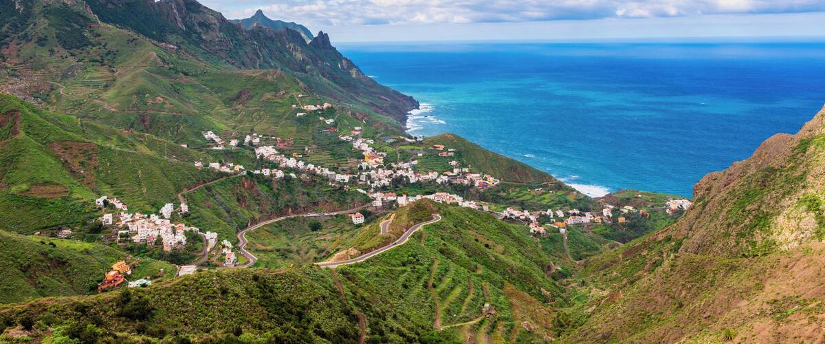 A coastal village nestled in green hills with a view of the ocean.