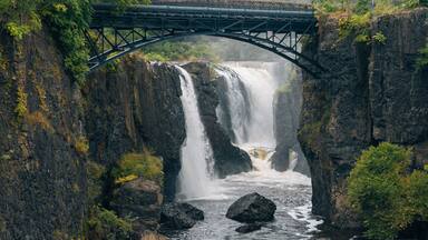 Un puente sobre una cascada, con acantilados rocosos y vegetación circundante.