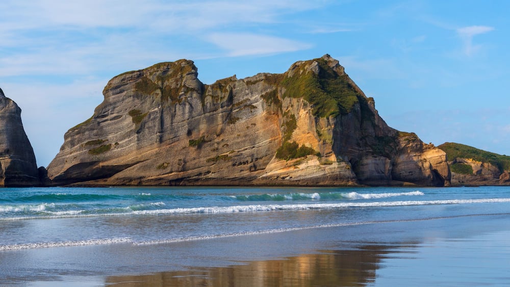 Un paysage côtier caractérisé par des formations rocheuses imposantes et une plage.