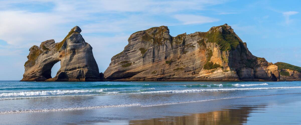A coastal landscape with prominent rock formations and a beach.