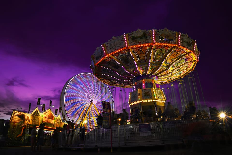 A brightly lit Ferris wheel and a carousel at night.