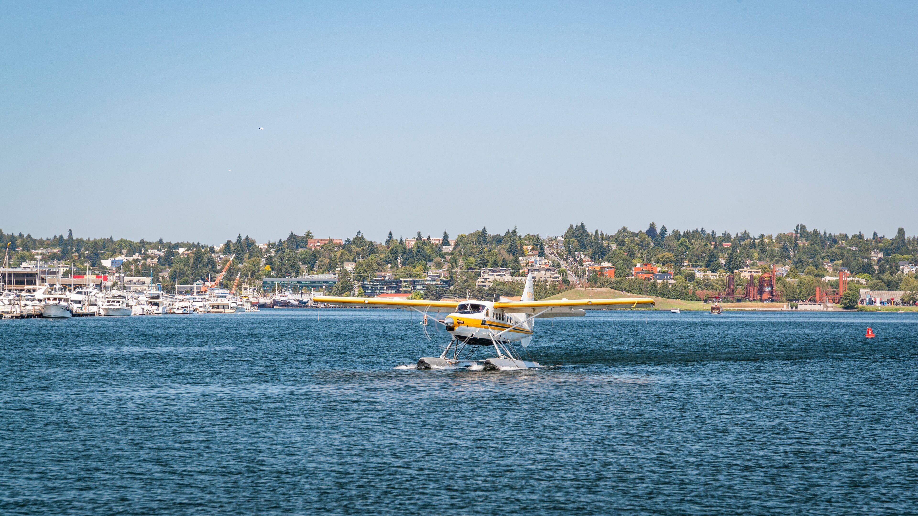 A seaplane on water with a cityscape in the background.