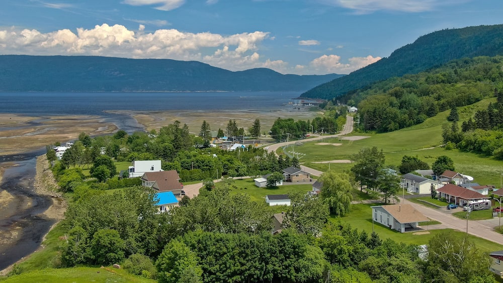 Une ville côtière avec des maisons, une plage et des montagnes en arrière-plan.