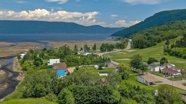 Uma vila costeira com casas, praia e montanhas ao fundo.
