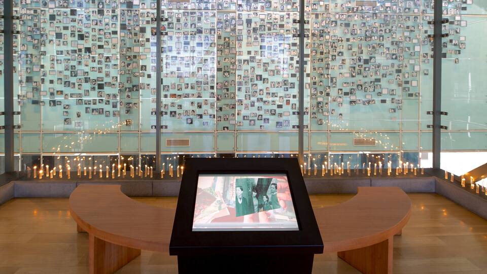 A memorial wall with numerous photographs and a digital display in the foreground.