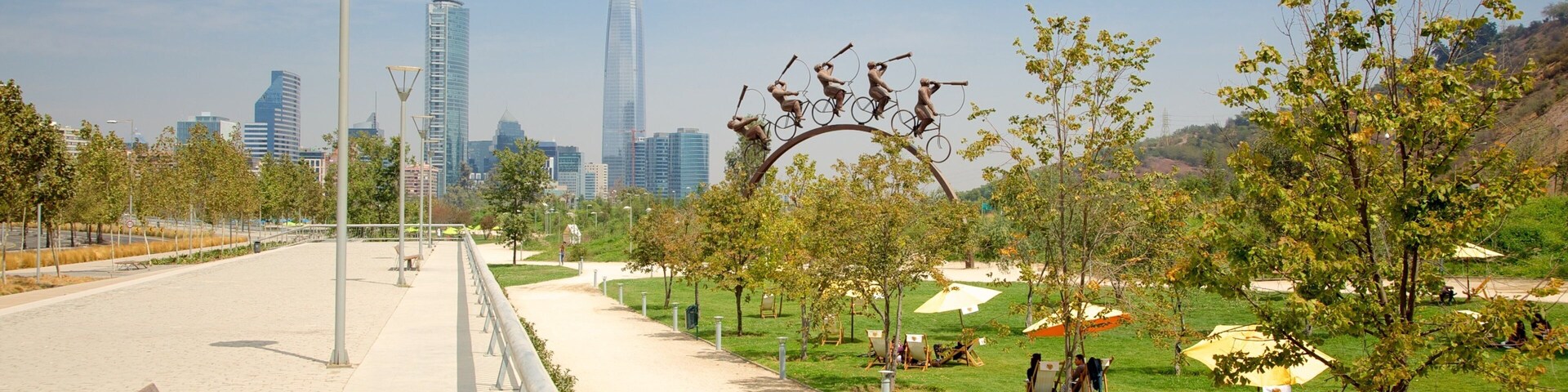 A park with a pathway, benches, trees, and a sculpture of people on bicycles.
