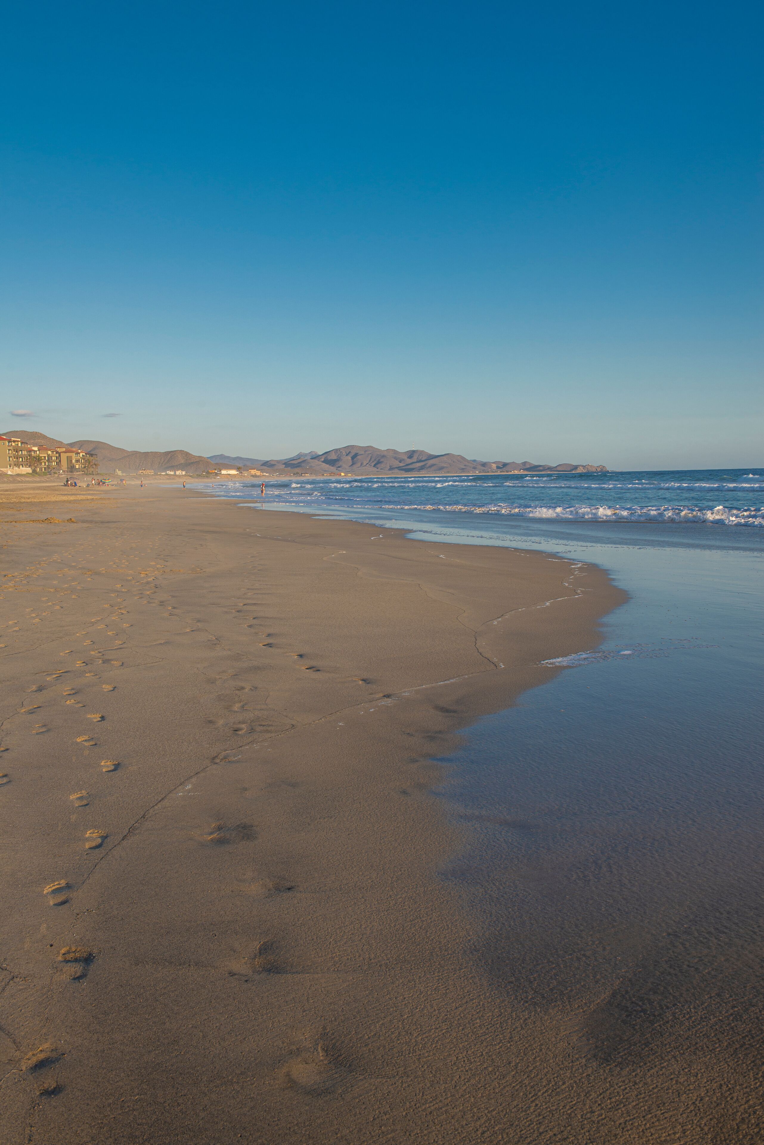 A calm sunset on the beach with ocean waves and mountains in the background Todos Santos Baja California Sur. Mexico