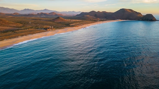 A coastal landscape with a beach, ocean, and distant mountains.