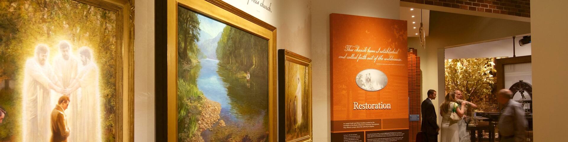 A gallery with framed paintings and a wooden wall with text.