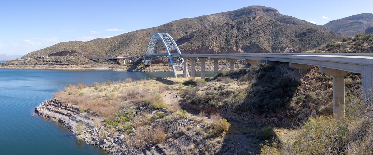 A bridge over a river with mountains in the background.