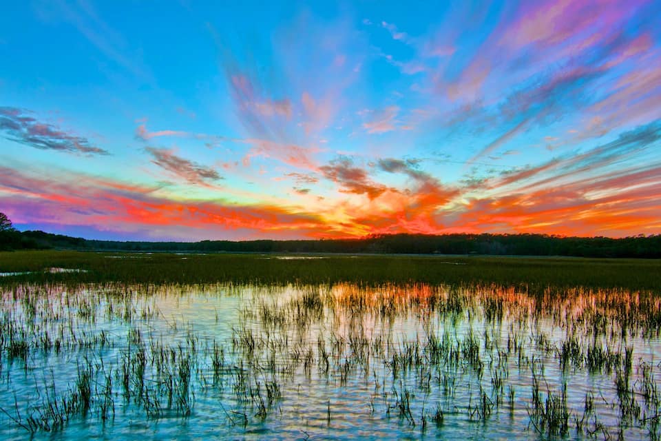 A sunset over a wetland with reflections of the sky.