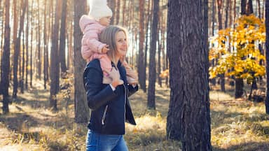 mother and little daughter are walking in a pine forest