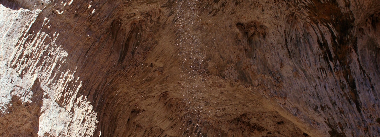 Una gran abertura de cueva con una cascada en su interior.