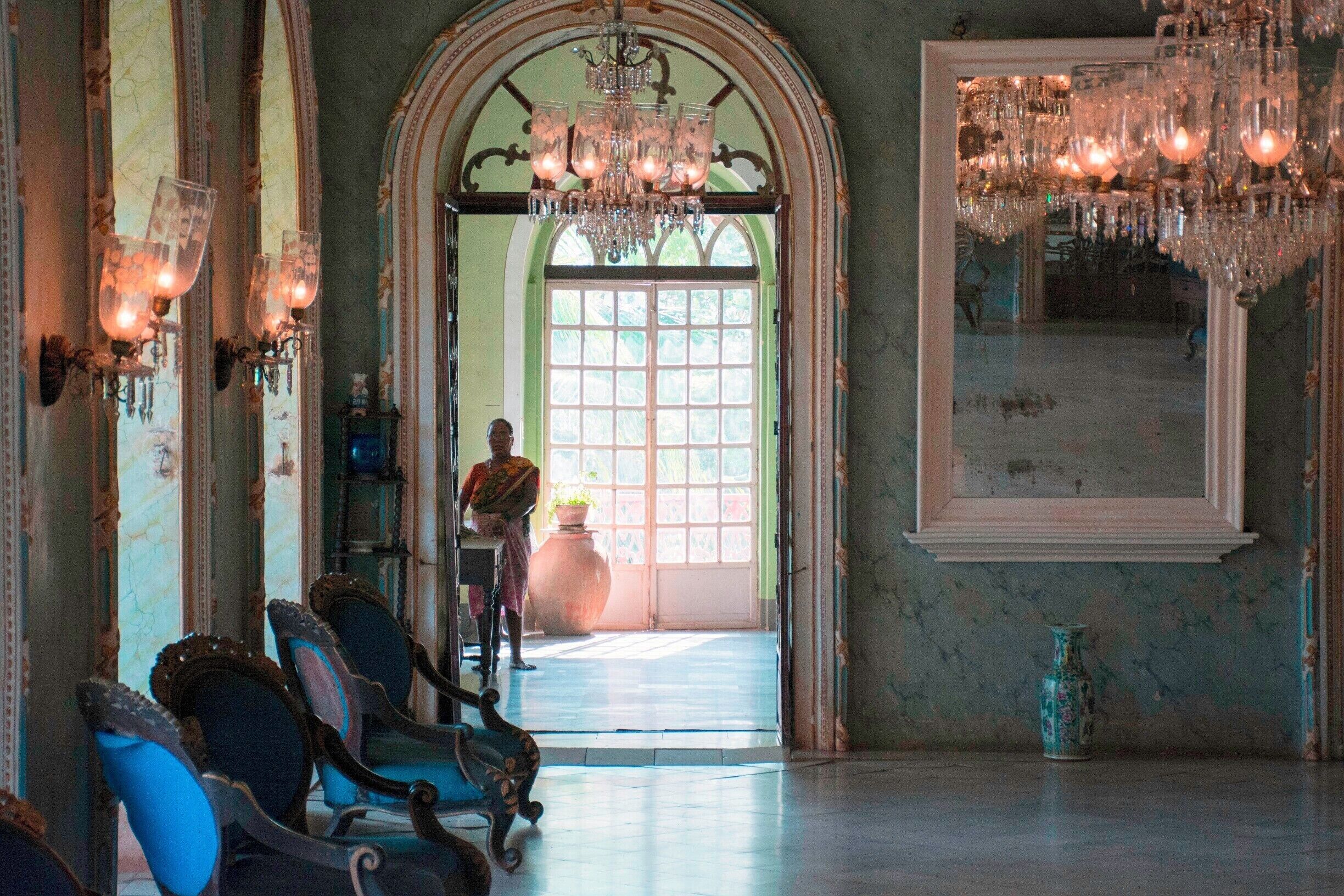 An ornate room with chandeliers, a large mirror, and classical furniture.