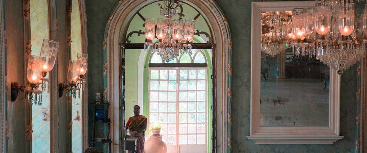 An ornate room with chandeliers, a large mirror, and classical furniture.