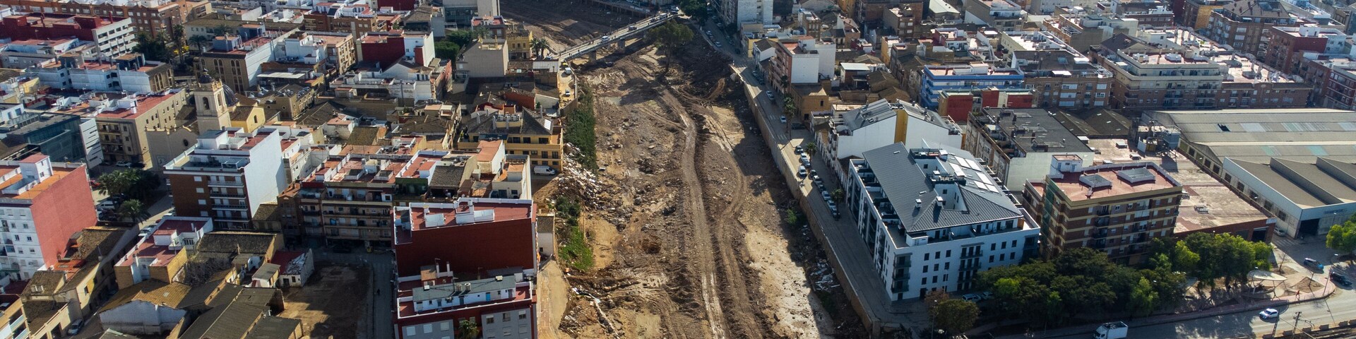 An aerial view of a city with a large construction site in the center, surrounded by dense urban buildings.