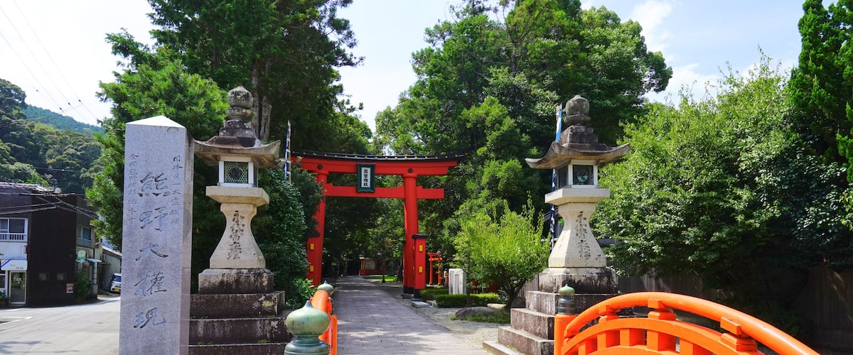 A traditional Japanese torii gate with a stone pathway leading through a lush green forest.