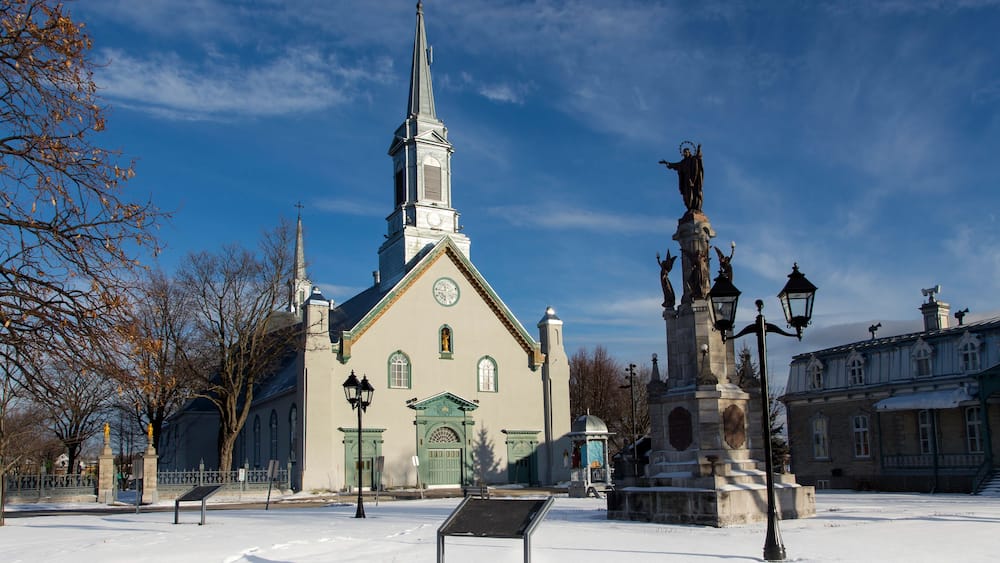 Town square with large 1816 neoclassical St-Augustin Church, patrimonial presbytery and statue on stone pedestal, Saint-Augustin-de-Desmaures, Quebec, Canada