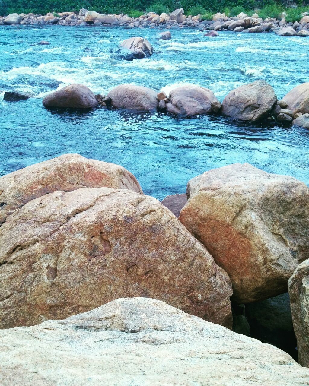 A river with clear blue water flowing over rocks.