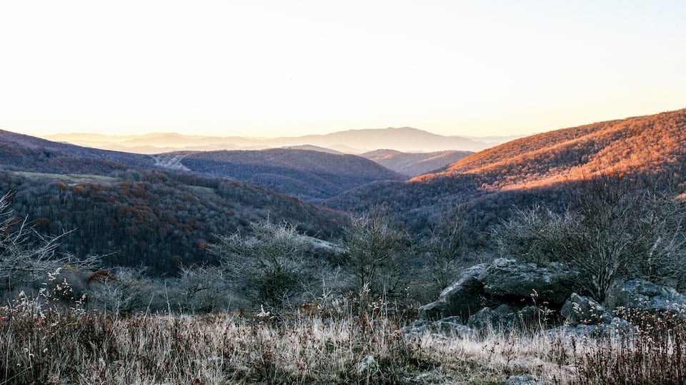 A mountainous landscape with a valley and distant hills.